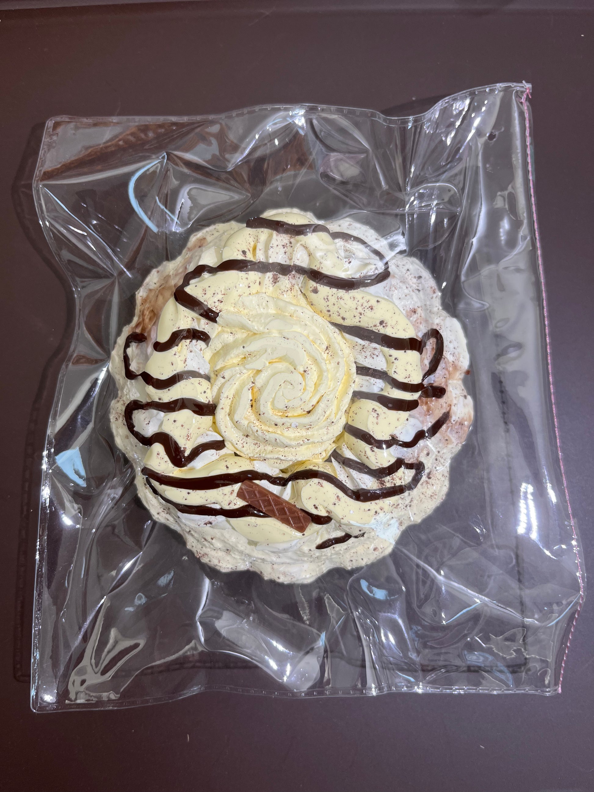 クリア袋入りの丸いデコレーション菓子、白いクリームにチョコ模様
