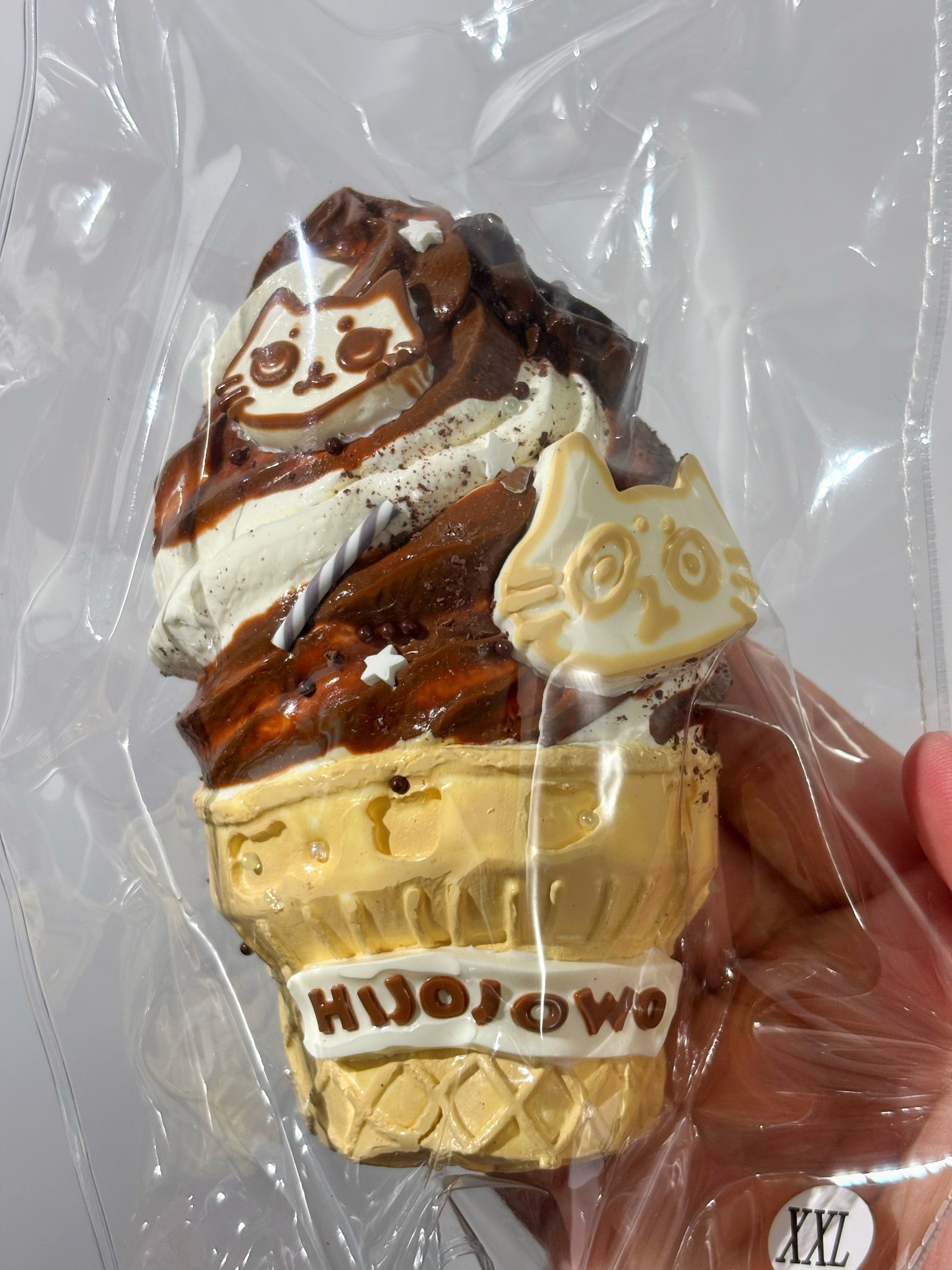 焼き菓子、三角のような形。チョコと白いキャラ飾り、上にHIJOJOWOロゴ