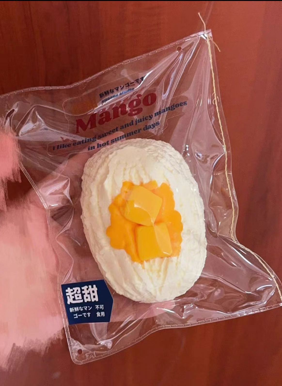 マンゴー風味の白い焼き菓子（半円、パッケージ入り、オレンジ具）