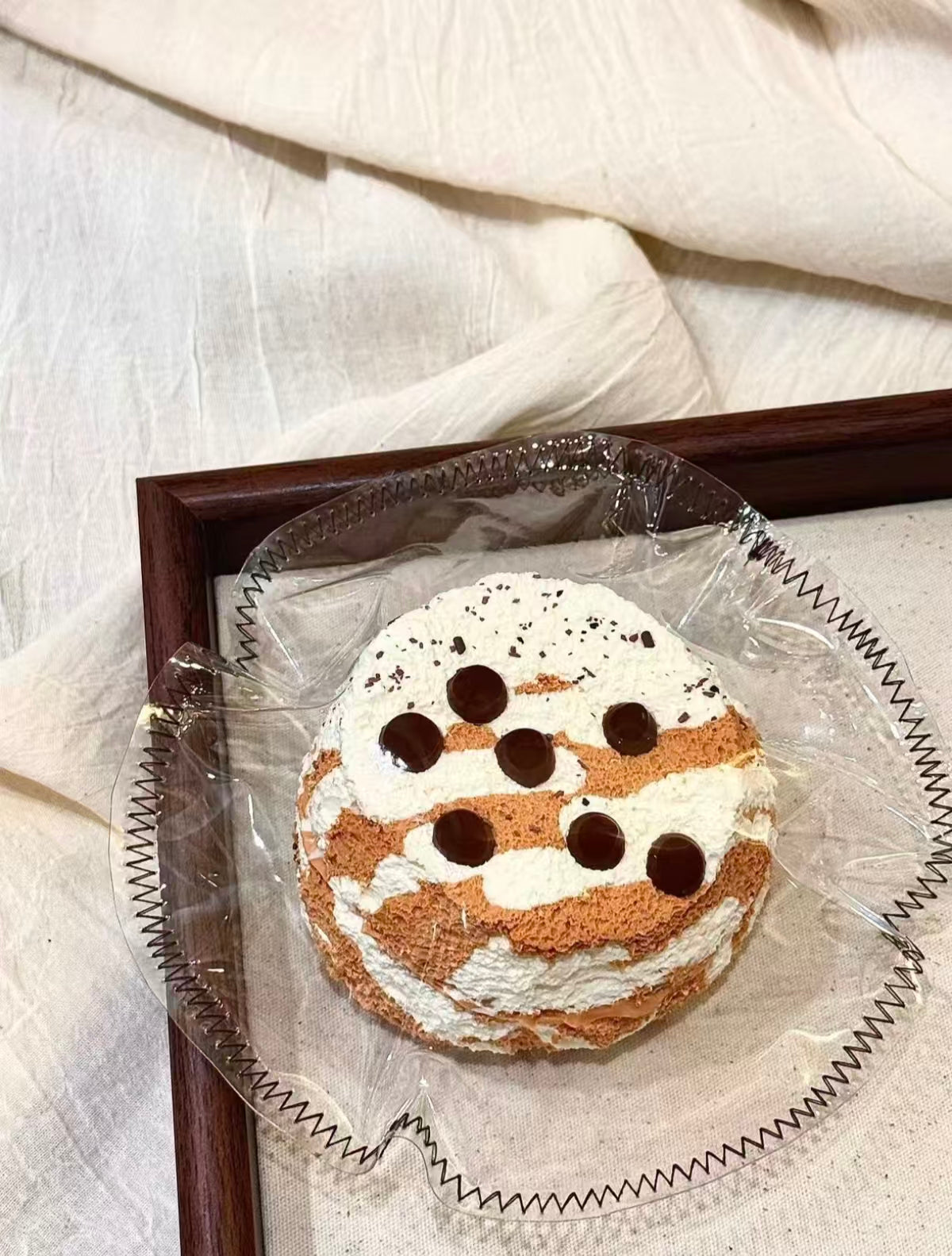 包装されたケーキスライス1点、白いクリームにチョコの丸い粒が並ぶ