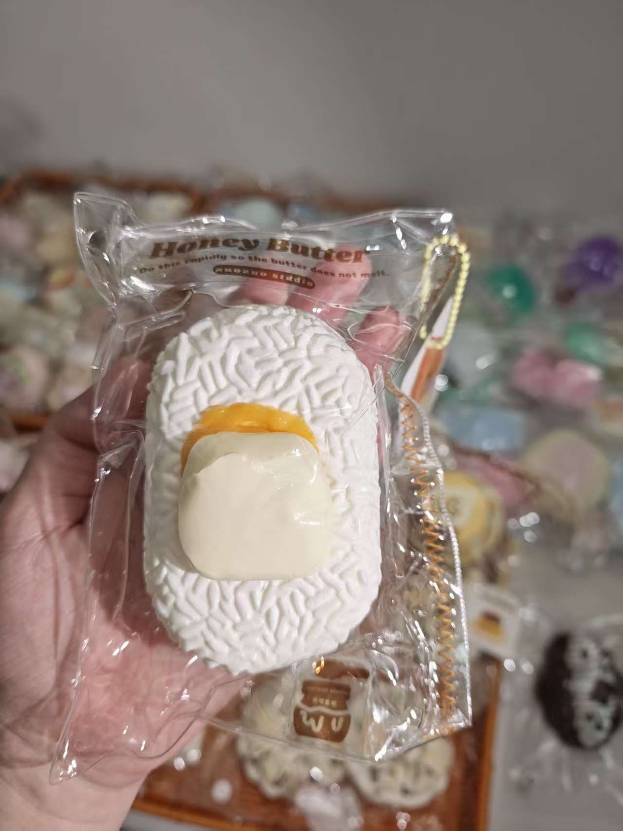 ハニーバター風味の白い焼き菓子（平形、パッケージ入り、オレンジ中央）