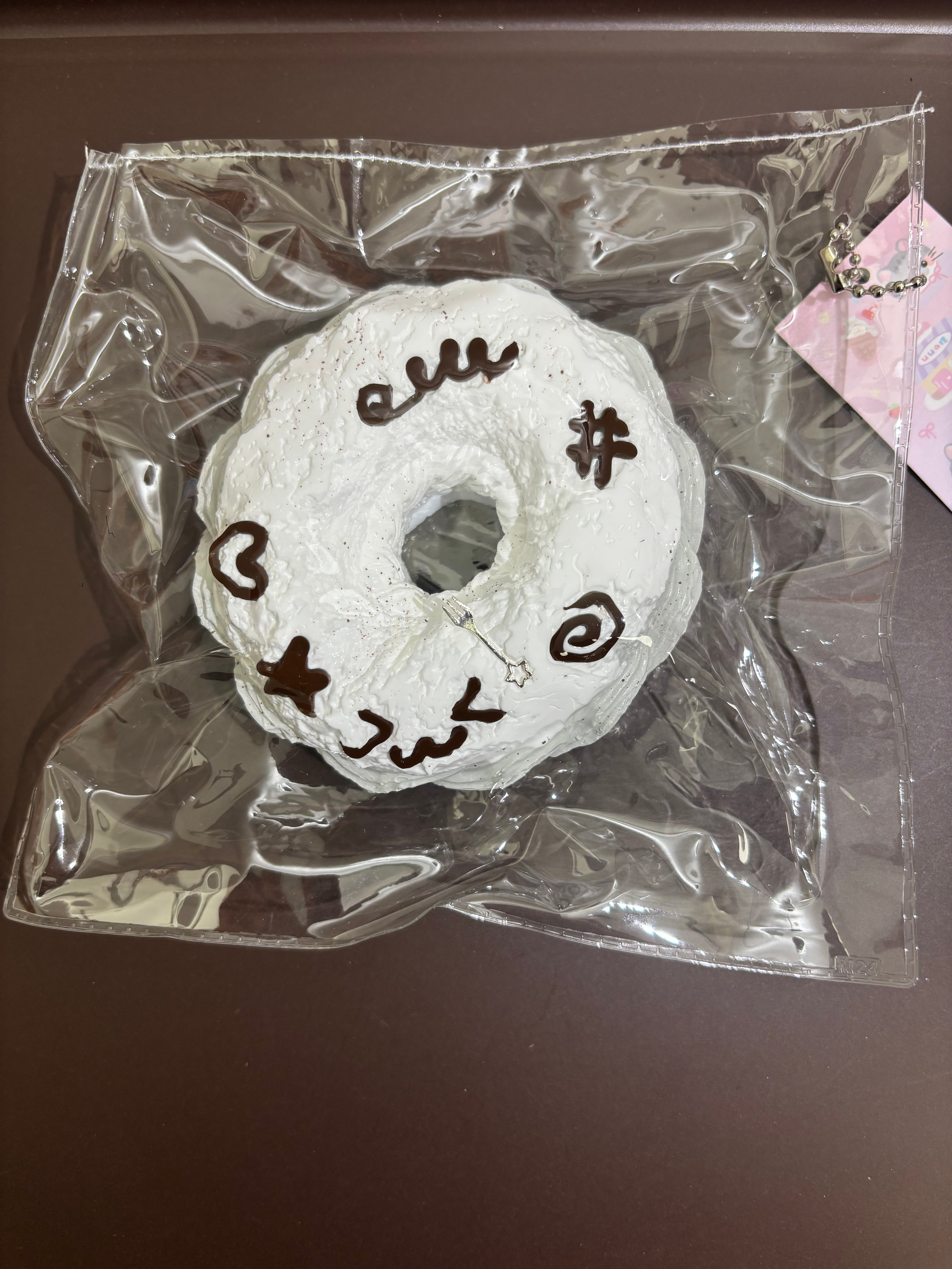 ドーナツ型の白い刺繍チャーム、中央の穴と文字・記号が見える（透明袋入り）